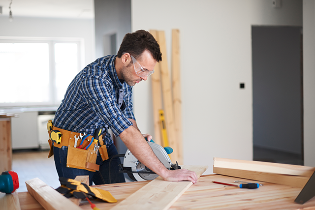 Carpenter Working with Circular Saw in a Well-Lit Workshop for Home Improvement