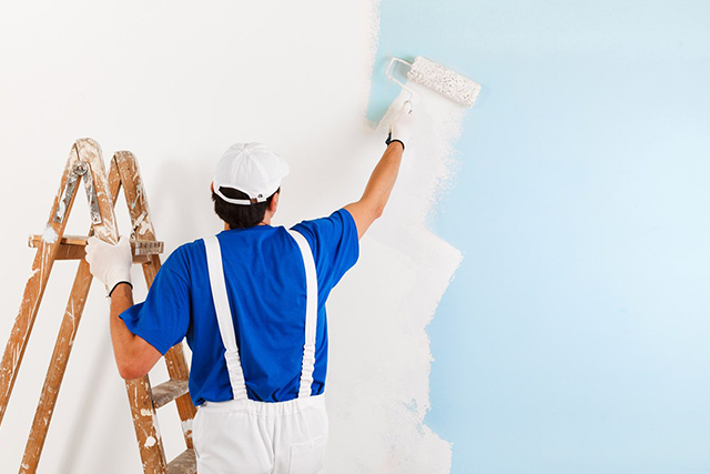 Painter Applying White Paint on Wall with Roller, Home Painting Services